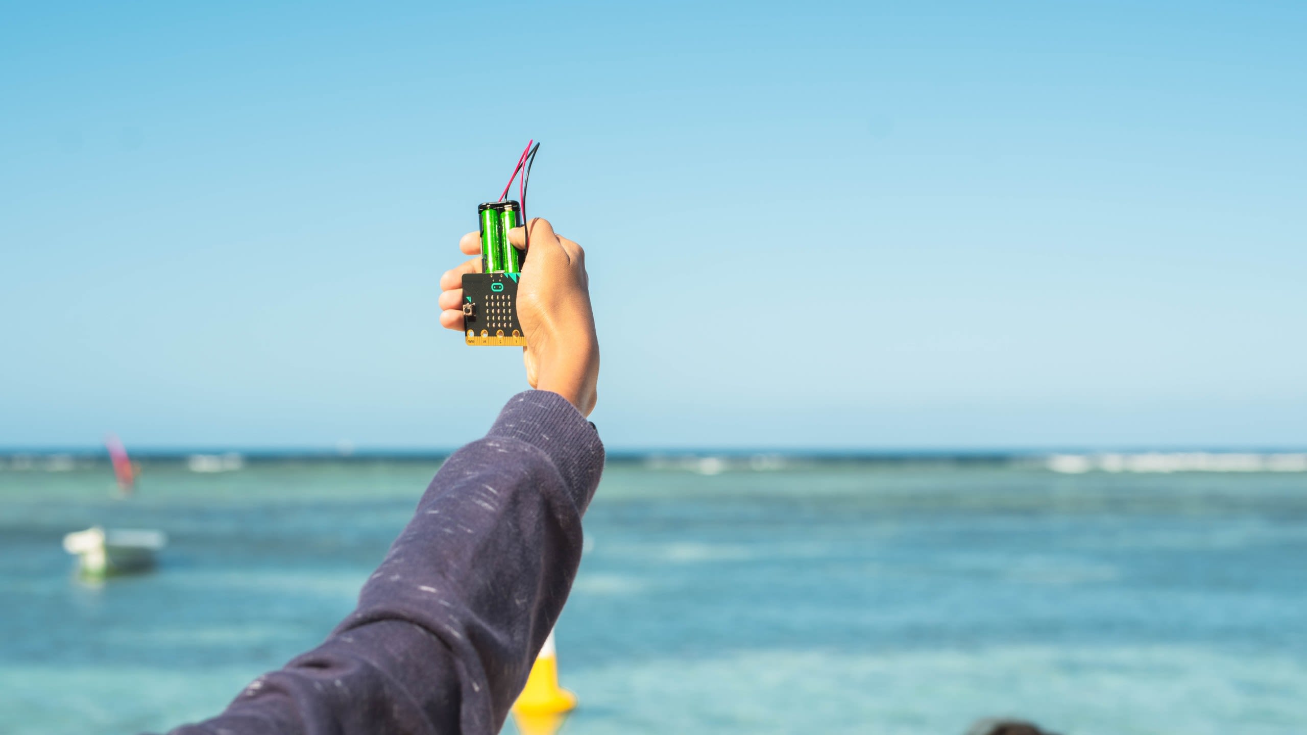 A micro:bit being held up in the air pointing to the sky.