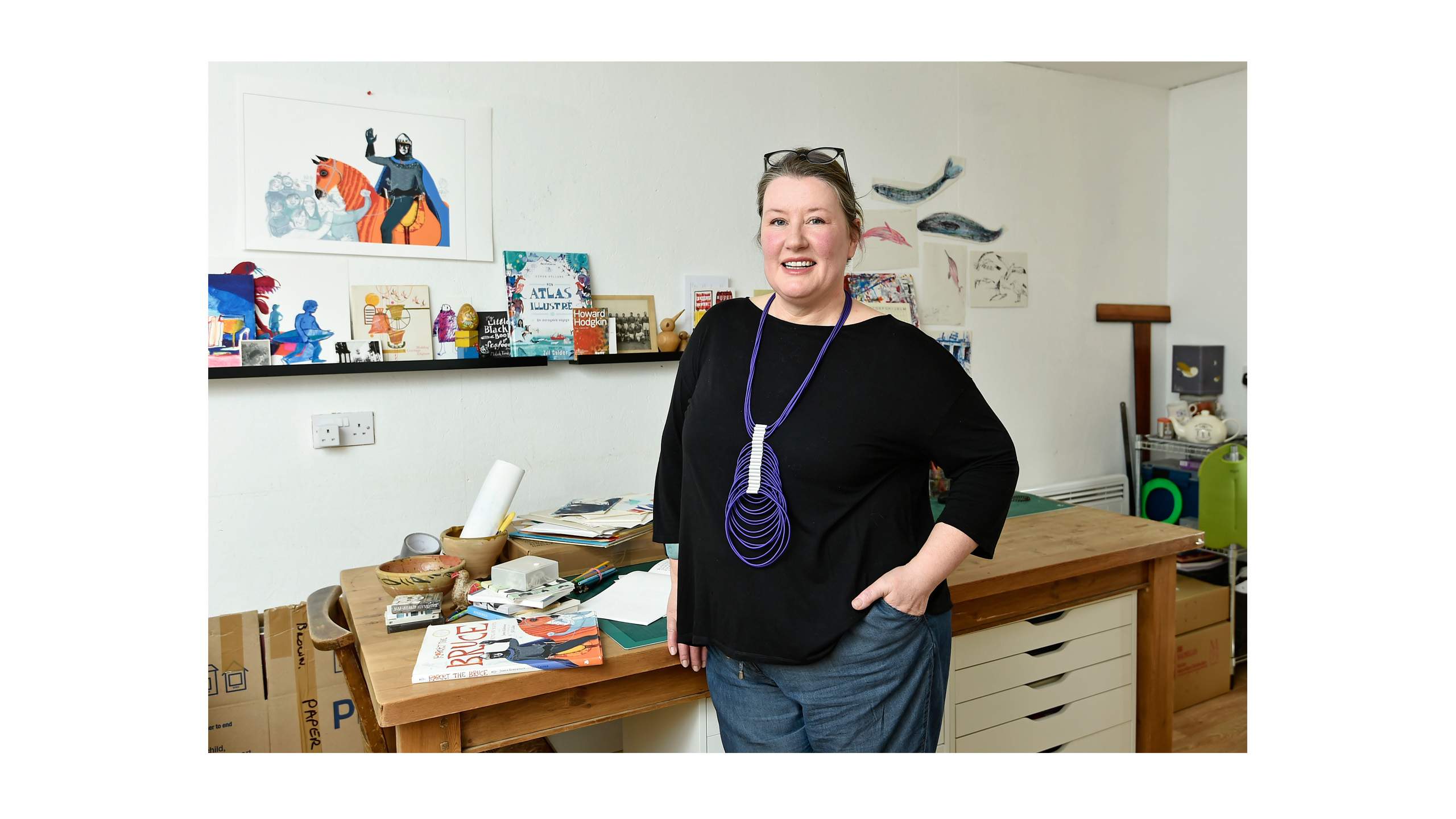 Photograph of artist Jill Calder in front of some of her work.