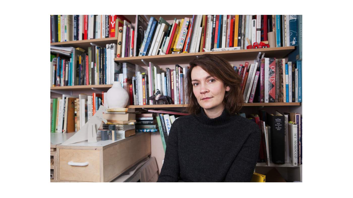 A photo of artist Laura Carlin in front of a bookcase.